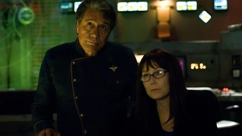 William Adama (Edward James Olmos) and Laura Roslin (Mary McDonnell) sit in a control room in Battlestar Galactica (2003)