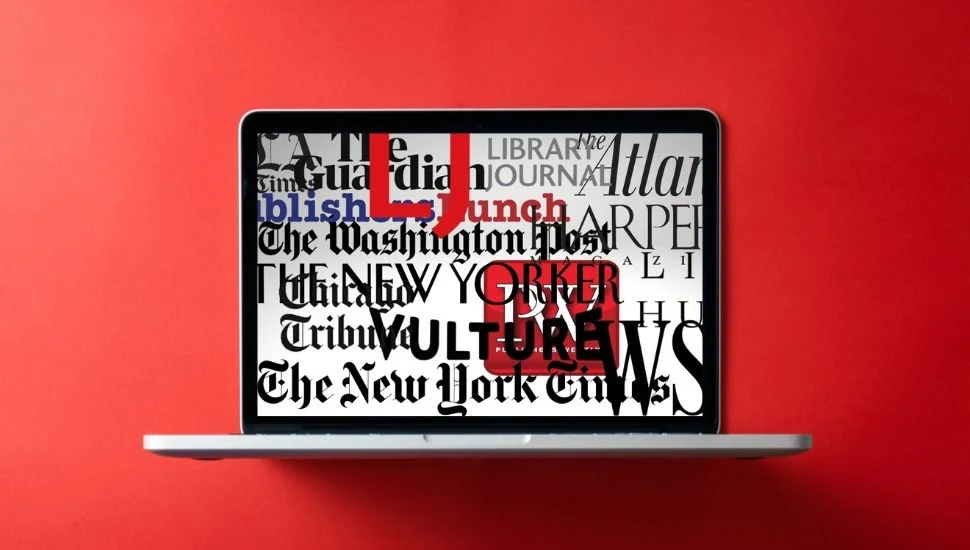a laptop computer with scattered headlines on its screen against a red background